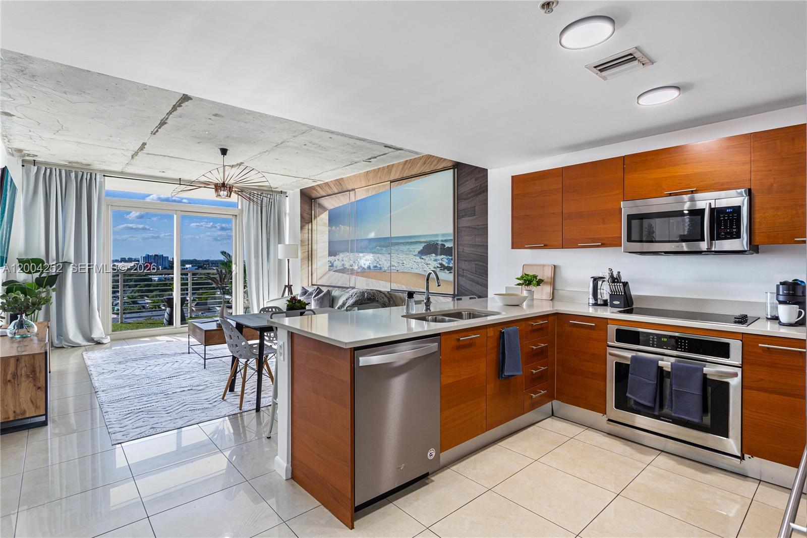An open-concept kitchen and living area features wood cabinets, stainless appliances, and a balcony view — 3250 NE 1st Ave # 913, Miami FL 33137, MIAMI, FL