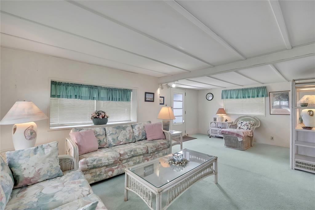 A living room features floral sofas, a glass coffee table, and light green carpeting — 37 WILLIAM PENN WAY UNIT 13, PALM HARBOR, FL