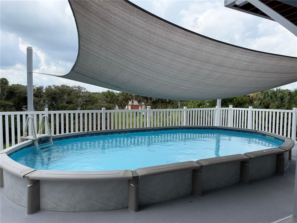 An oval above-ground swimming pool sits on a patio under a large shade sail — 2446 S CENTRAL AVENUE, FLAGLER BEACH, FL