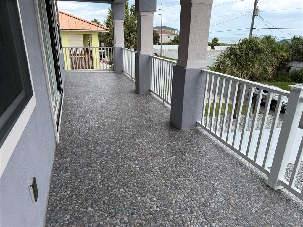 A two-story lavender house features a balcony, two garage doors, and a gravel driveway — 2446 S CENTRAL AVENUE, FLAGLER BEACH, FL