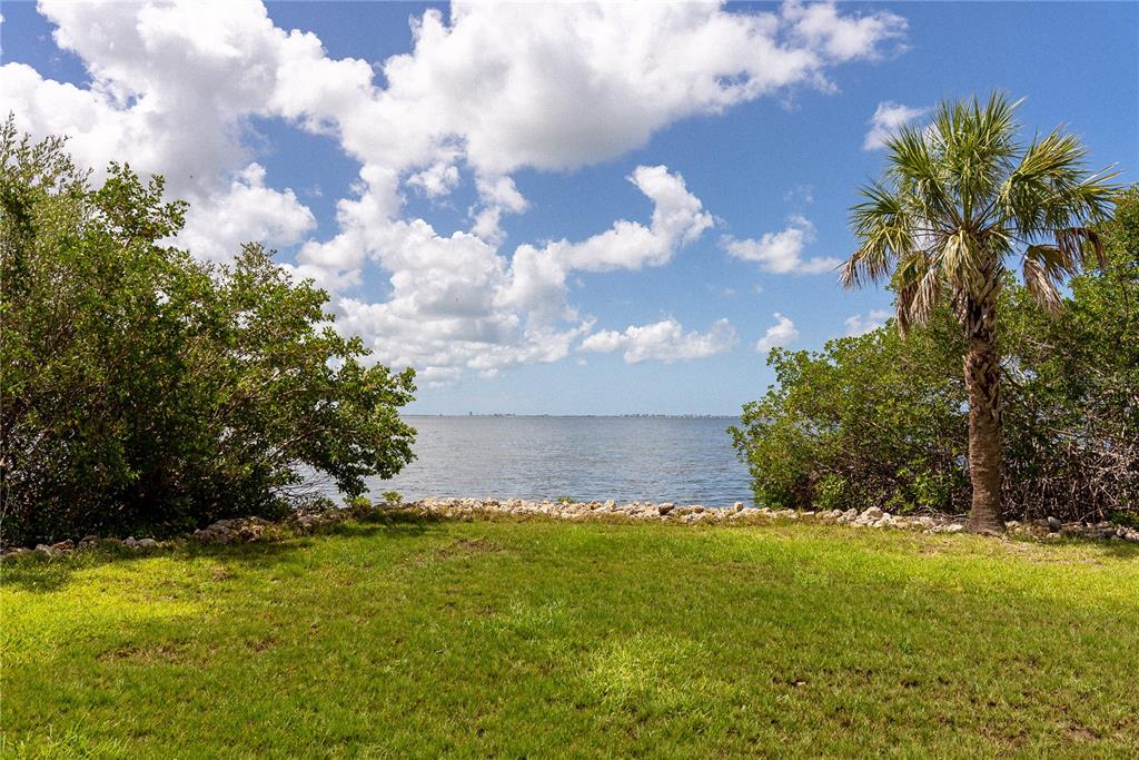 A grassy lawn leads to a rocky shoreline overlooking a large body of water — 2424 BAY DRIVE UNIT 2424/2426, BRADENTON, FL