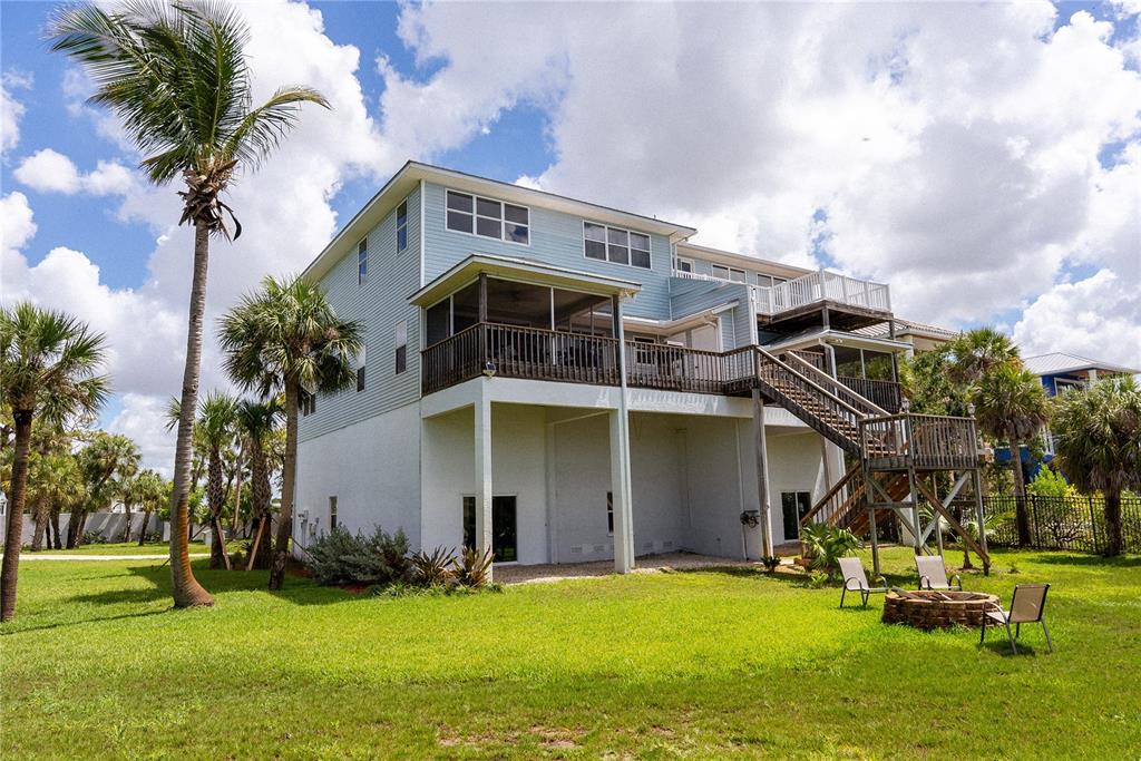 A light blue multi-story house with a raised deck, screened porch, and backyard fire pit — 2424 BAY DRIVE UNIT 2424/2426, BRADENTON, FL
