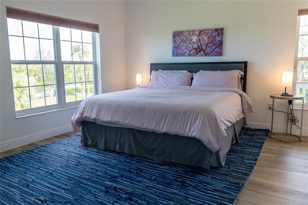 A bedroom features a bed with lavender bedding, a blue rug, and two windows — 2424 BAY DRIVE UNIT 2424/2426, BRADENTON, FL