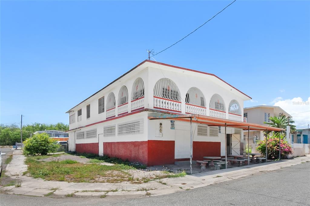 A two-story building with a red base, white upper walls, and arched balcony railings — 638 CALLE B COM. SERRANO, JUANA DIAZ, PR