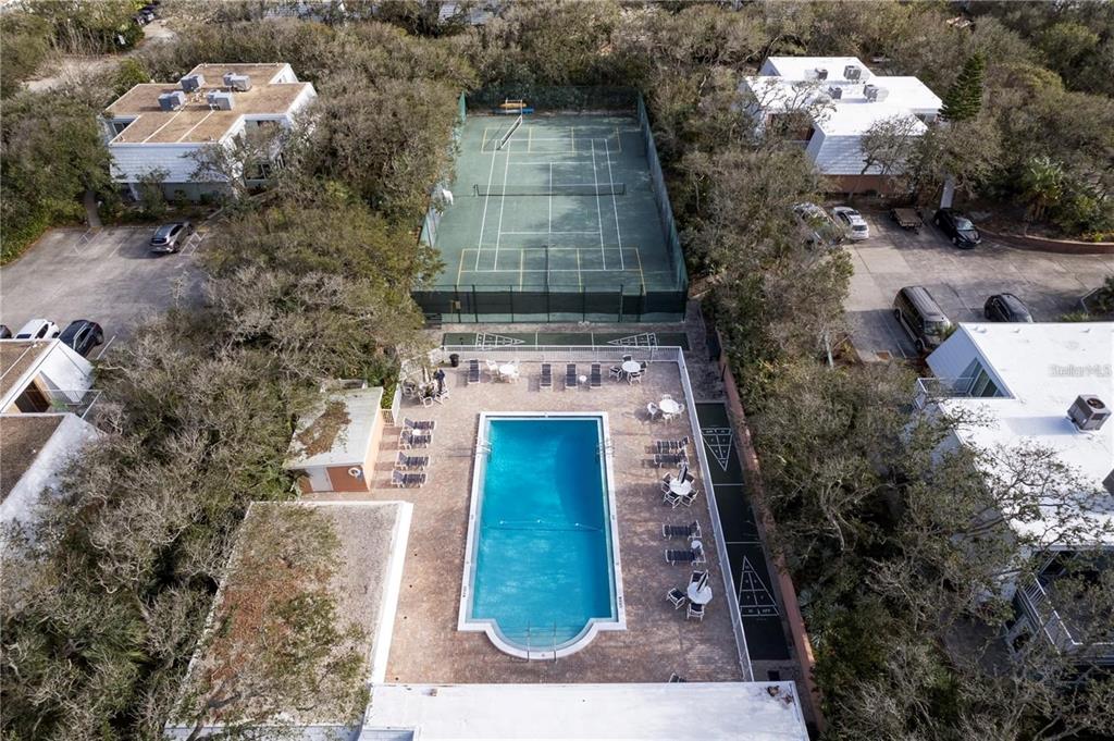 An aerial view shows a swimming pool, a tennis court, and surrounding residential buildings — 4150 S ATLANTIC AVENUE UNIT 104 B, NEW SMYRNA BEACH, FL