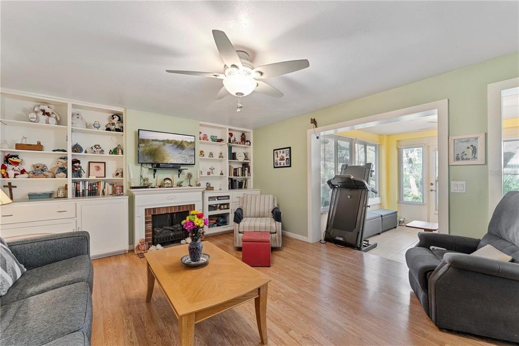 A living room with a fireplace, built-in shelves, wood flooring, and a ceiling fan — 4150 S ATLANTIC AVENUE UNIT 104 B, NEW SMYRNA BEACH, FL