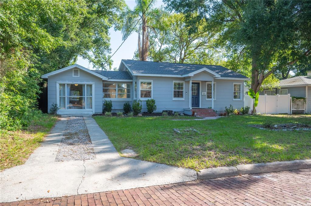 A single-story gray house with a gravel driveway and a brick street in front — 1037 JOSEPHINE STREET, LAKELAND, FL