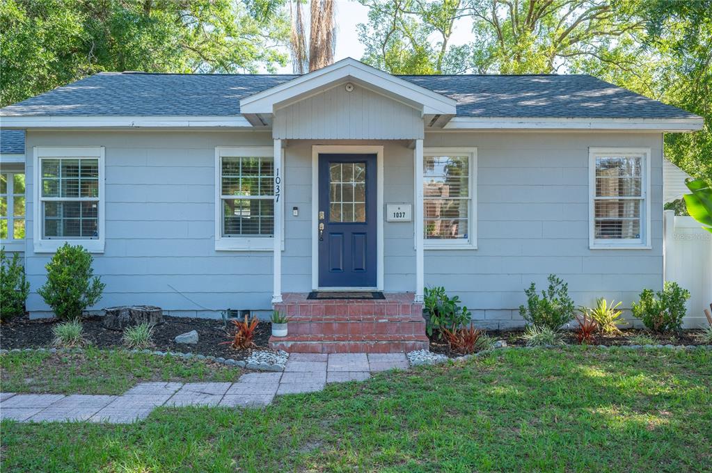 A single-story house with gray siding, a blue front door, and a brick porch — 1037 JOSEPHINE STREET, LAKELAND, FL