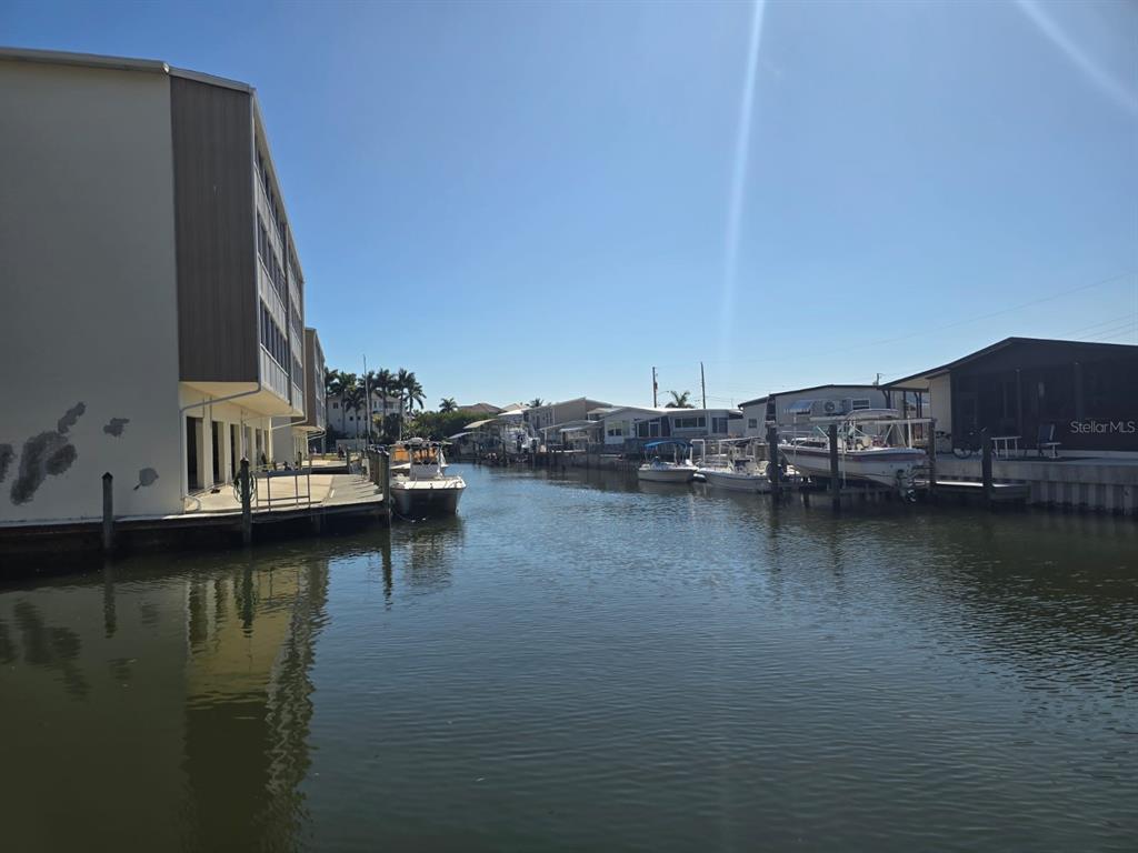A canal view shows a multi-story building on the left and several boats docked nearby — 1714 69TH AVENUE W UNIT A204, BRADENTON, FL