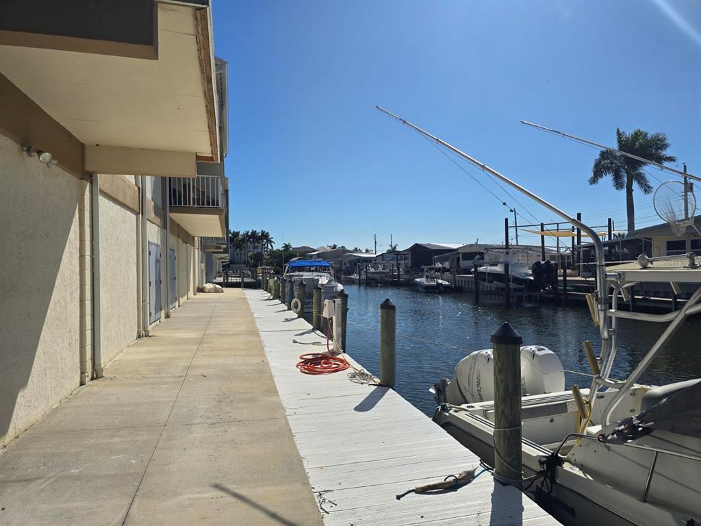 A concrete walkway runs alongside a canal with docked boats and a building exterior — 1714 69TH AVENUE W UNIT A204, BRADENTON, FL