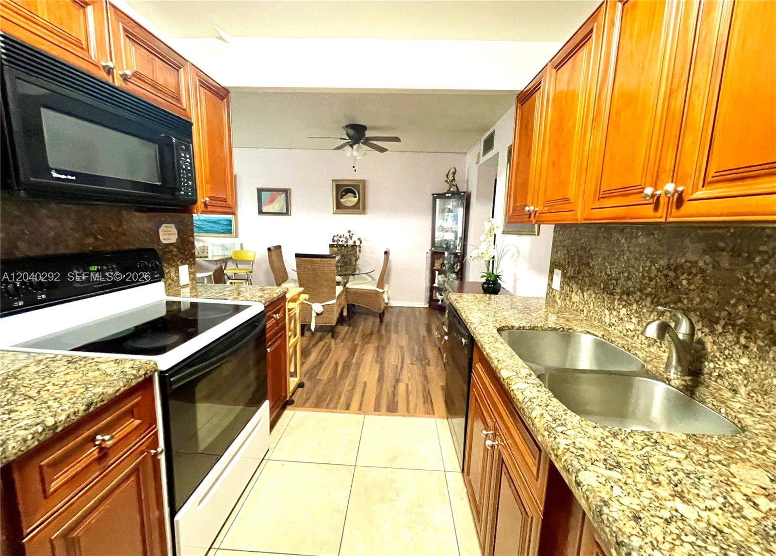 A kitchen with wood cabinets and granite countertops opens into a dining area — 4031 Harwood D # 4031, Deerfield Beach FL 33442, DEERFIELD BEACH, FL