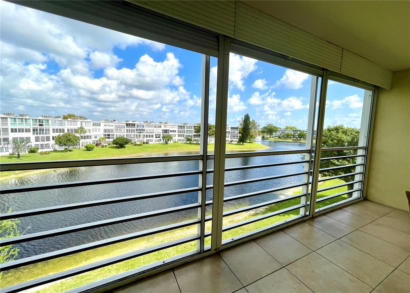 A tiled balcony overlooks a lake and residential buildings under a blue sky — 4031 Harwood D # 4031, Deerfield Beach FL 33442, DEERFIELD BEACH, FL