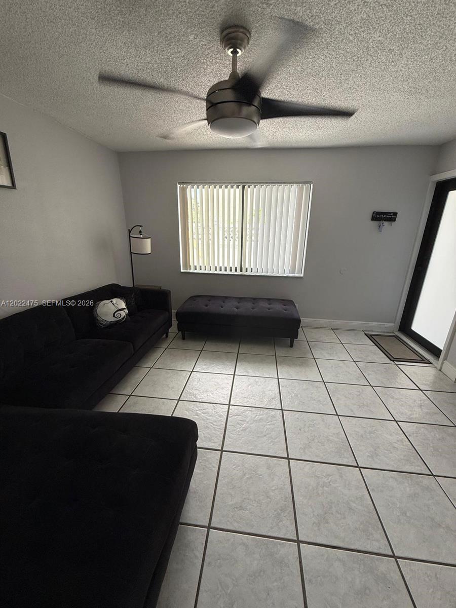 An open-concept room features light gray walls, white tiled floors, and a ceiling fan — 9116 NW 35th Pl # 0, Sunrise FL 33351, SUNRISE, FL