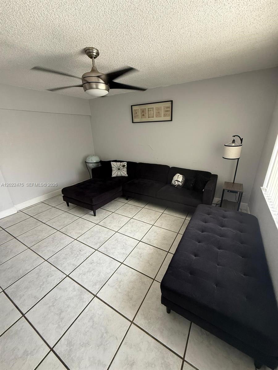 An open-concept living and dining area features light gray walls and large white floor tiles — 9116 NW 35th Pl # 0, Sunrise FL 33351, SUNRISE, FL