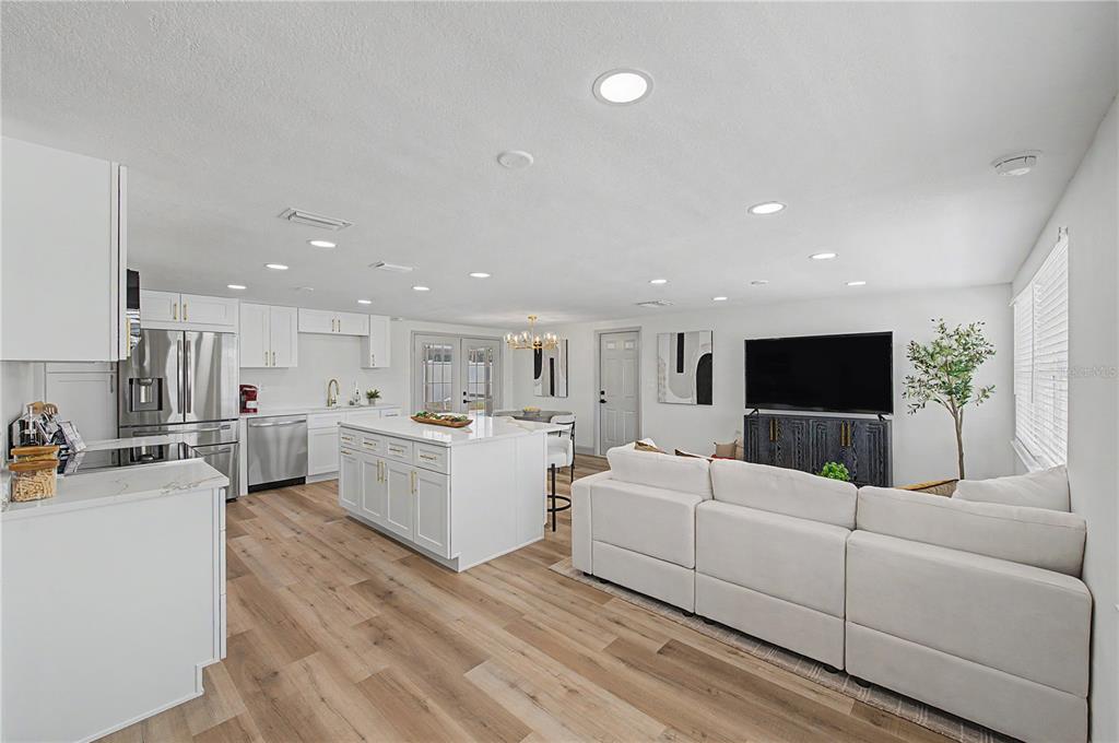 An open-concept kitchen and living area features white cabinetry, a central island, and wood flooring — 2619 ALBION STREET, HOLIDAY, FL