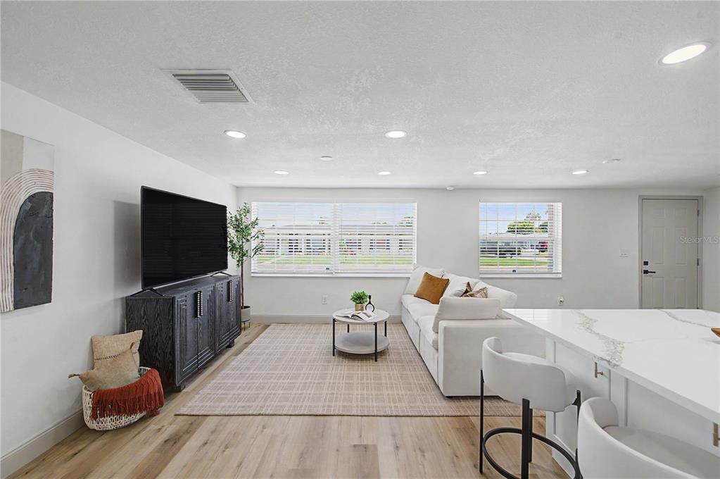 A bright living room features a white sofa, a television on a dark cabinet, and flooring — 2619 ALBION STREET, HOLIDAY, FL