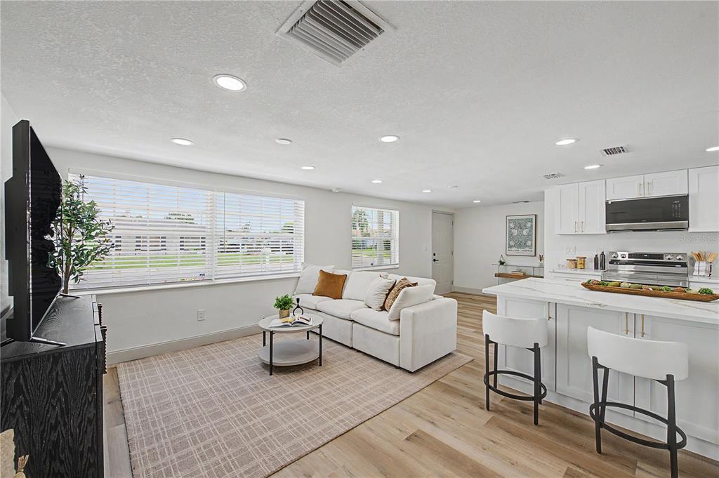 An open-concept living room and kitchen featuring white cabinetry, a kitchen island, and wood flooring — 2619 ALBION STREET, HOLIDAY, FL
