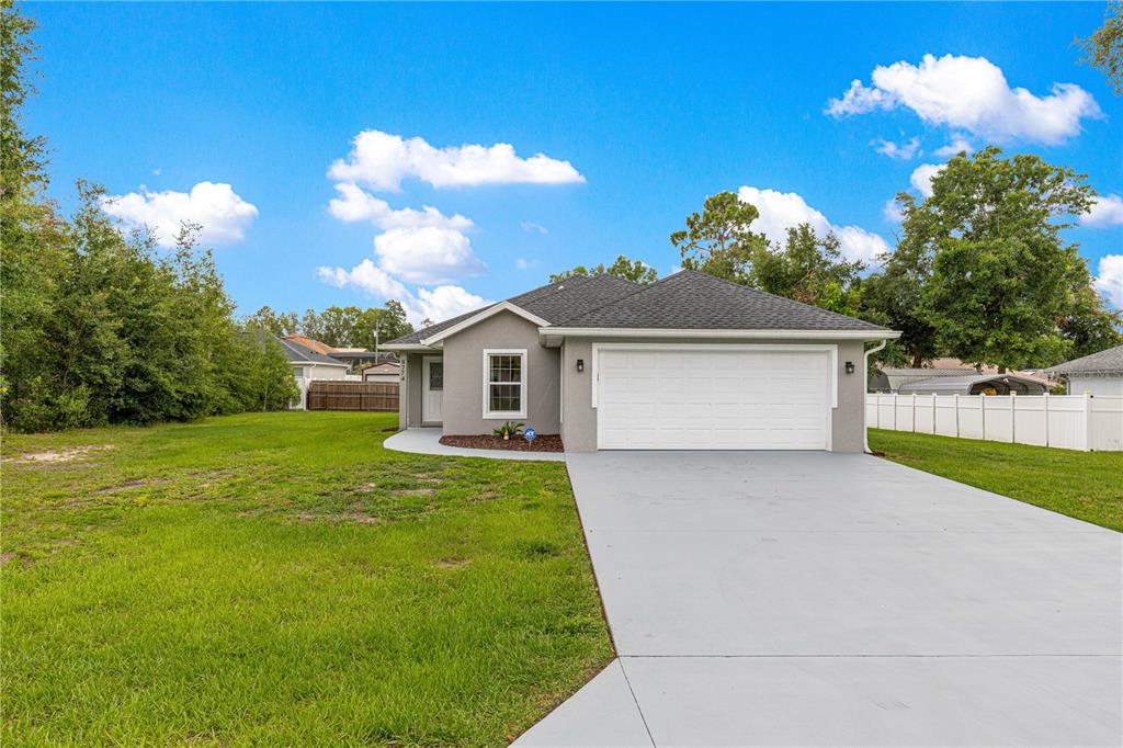 A single-story house with a gray exterior, white garage door, and a concrete driveway — 8774 SE 162ND STREET, SUMMERFIELD, FL