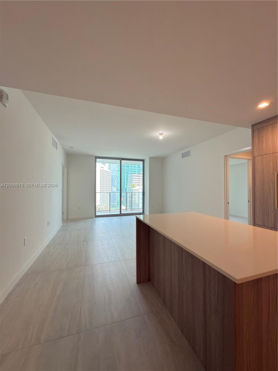 This interior view shows a kitchen island with light countertops and tile flooring — 77 SE 5th St # 1602, Miami FL 33131, MIAMI, FL