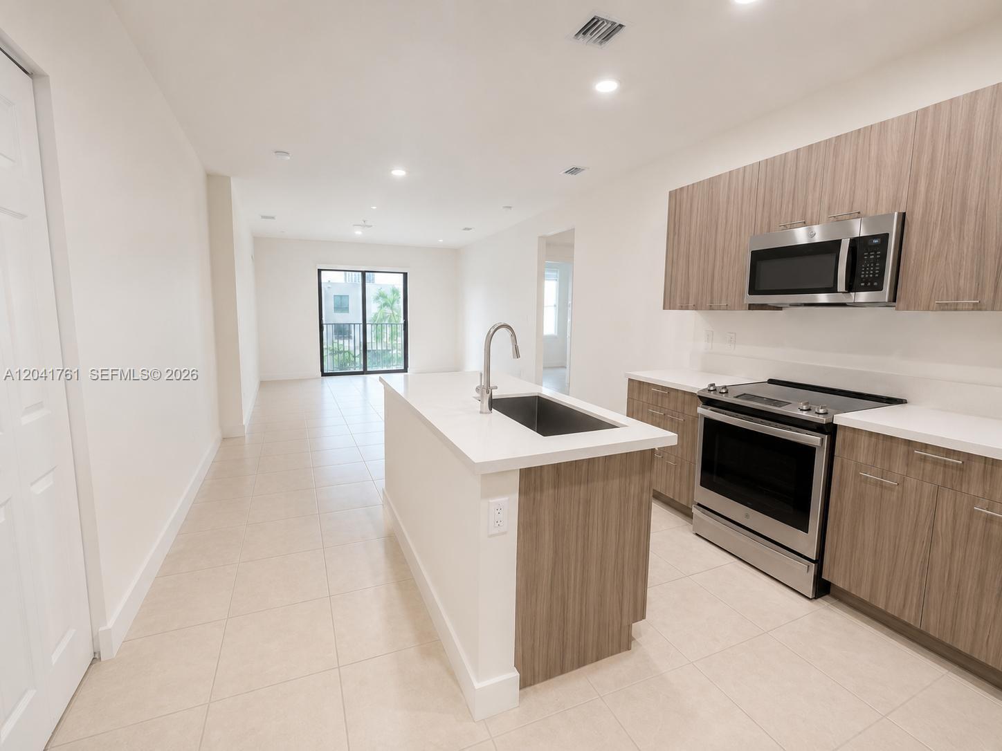 A modern kitchen features wood-grain cabinets, stainless steel appliances, and a white quartz island — 4636 NW 84th Ave # 45, Doral FL 33166, DORAL, FL