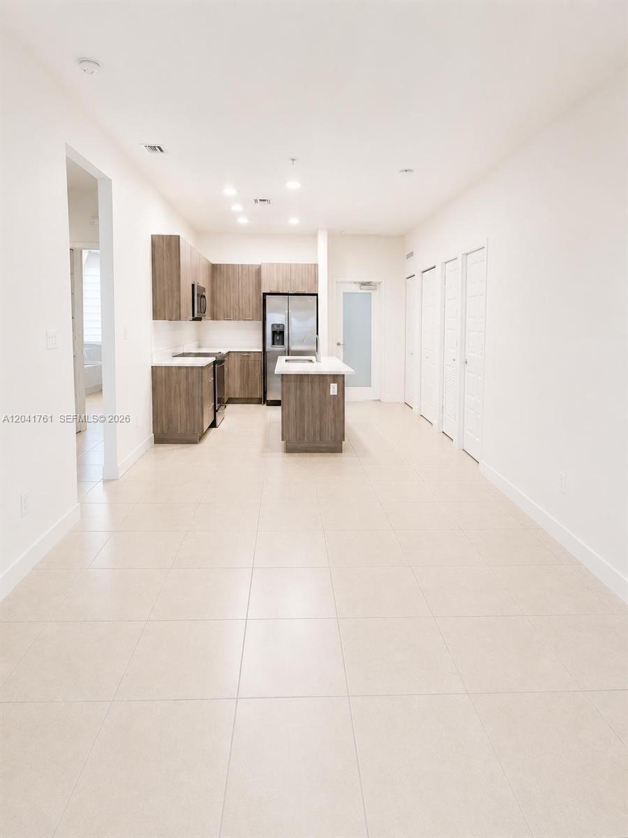 A modern kitchen features wood-toned cabinetry, stainless steel appliances, and a central island — 4636 NW 84th Ave # 45, Doral FL 33166, DORAL, FL