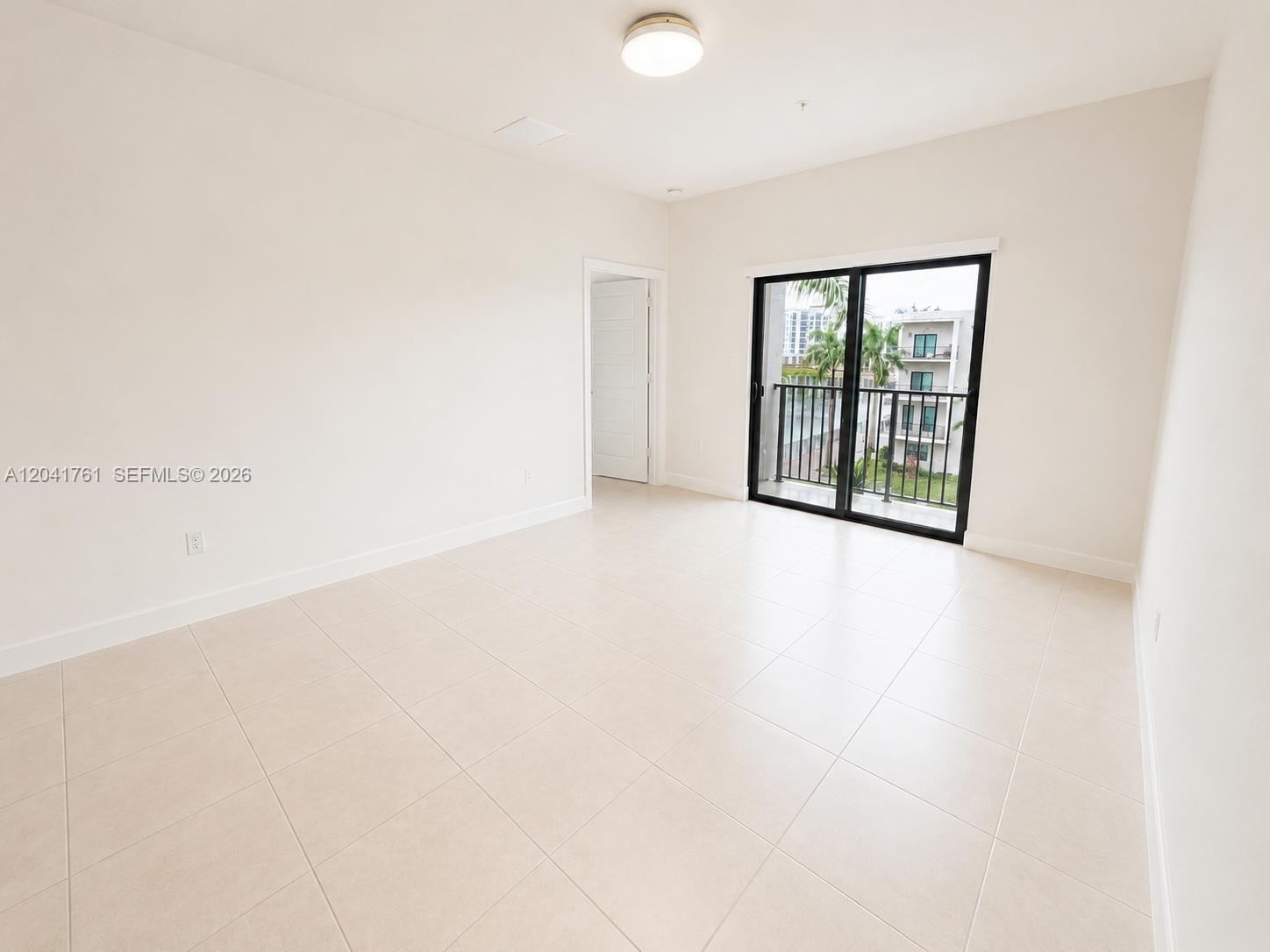 An empty room with light tile flooring, a ceiling light, and a sliding glass door — 4636 NW 84th Ave # 45, Doral FL 33166, DORAL, FL