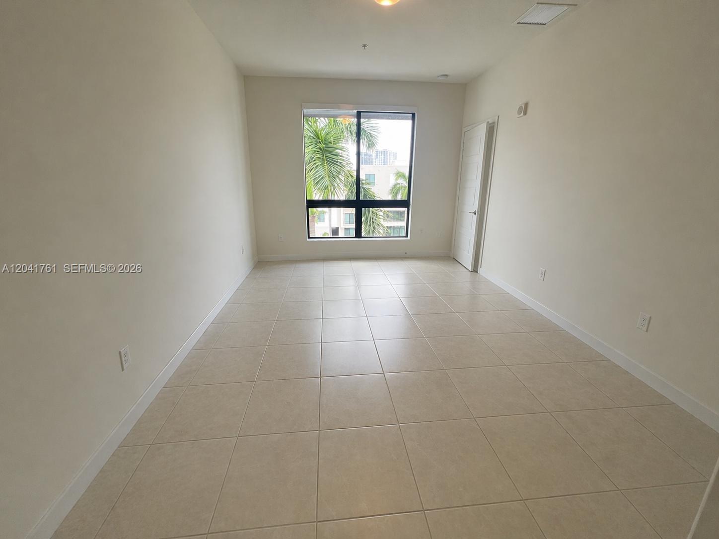 An empty room with beige tile flooring, white walls, and a large window overlooking palms — 4636 NW 84th Ave # 45, Doral FL 33166, DORAL, FL