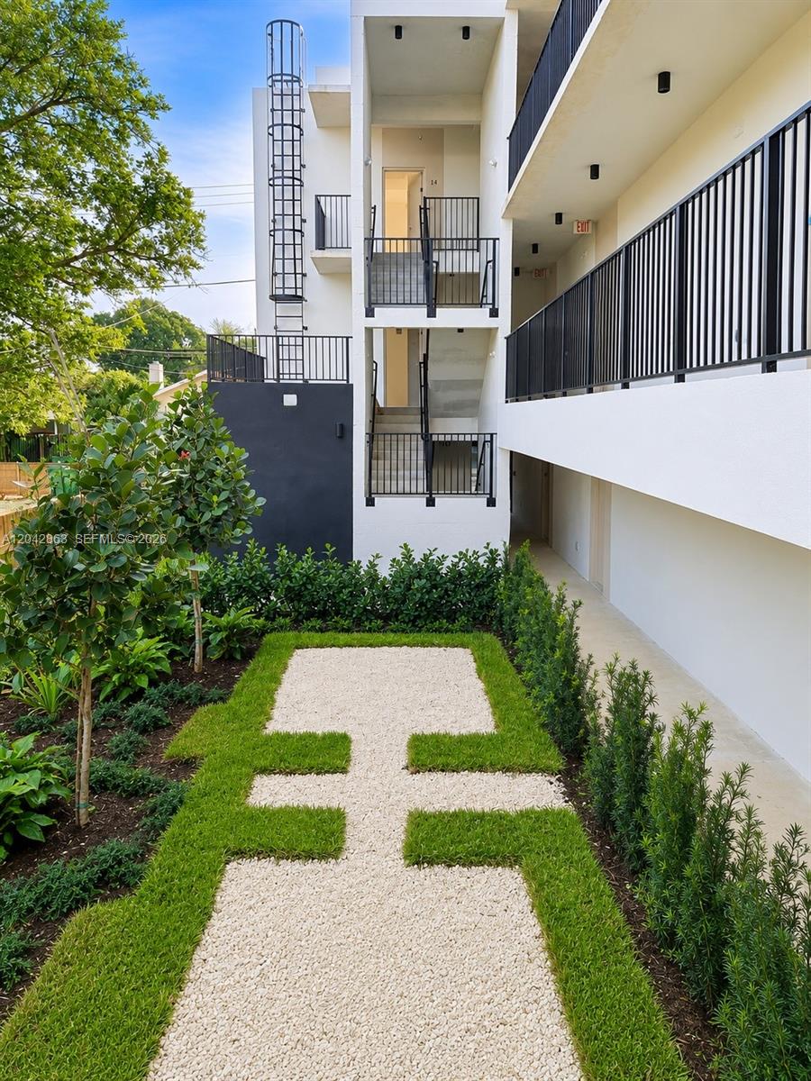 A modern apartment building exterior features a gravel walkway, manicured lawn, and metal staircases — 8106 NE 1st Ave # 2, Miami FL 33138, MIAMI, FL