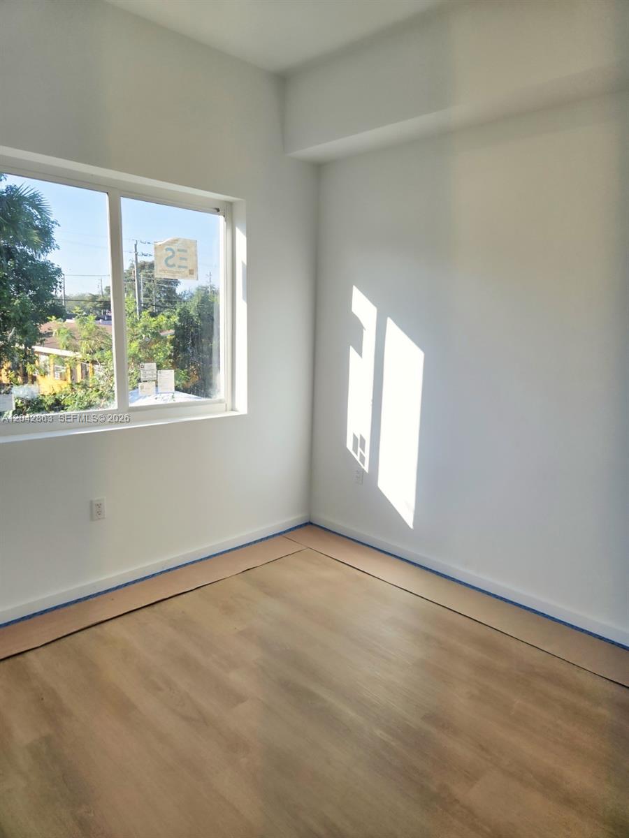 An empty room features white walls, light wood-look flooring, and a window with exterior views — 8106 NE 1st Ave # 2, Miami FL 33138, MIAMI, FL