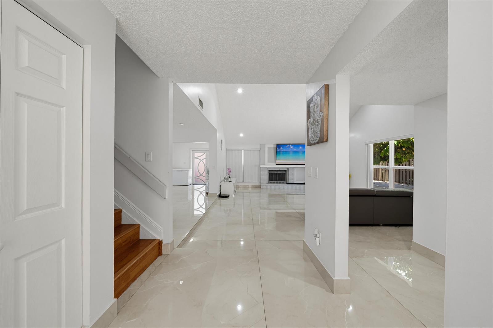 A bright entryway with light tile floors leads to a living area with a fireplace — 8811 SW 150th Place Circle, Miami FL 33196, MIAMI, FL