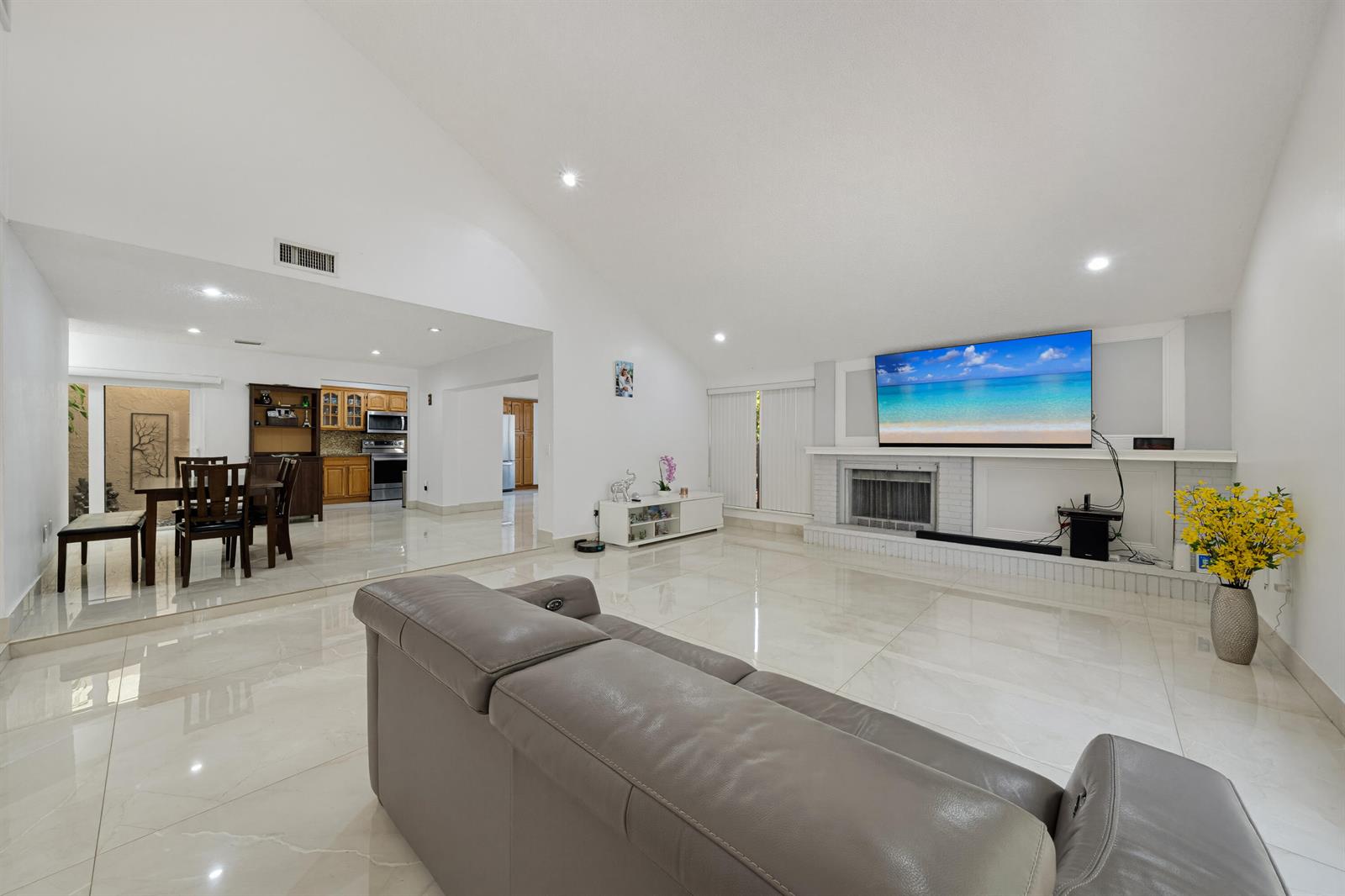 A spacious living room with white tile floors, a vaulted ceiling, and a fireplace — 8811 SW 150th Place Circle, Miami FL 33196, MIAMI, FL