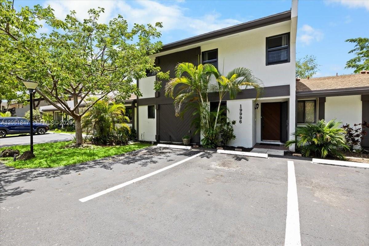 A two-story building with white and dark brown exterior walls sits behind a parking lot — 19996 NE 5th Ct # 4C, Miami FL 33179, MIAMI, FL