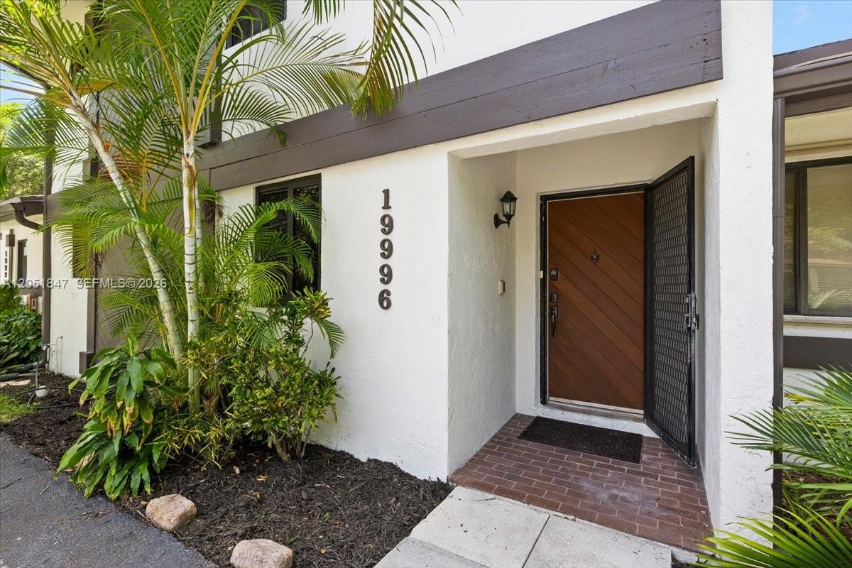 The exterior of a home features a brown door, brick entryway, and vertical house numbers — 19996 NE 5th Ct # 4C, Miami FL 33179, MIAMI, FL