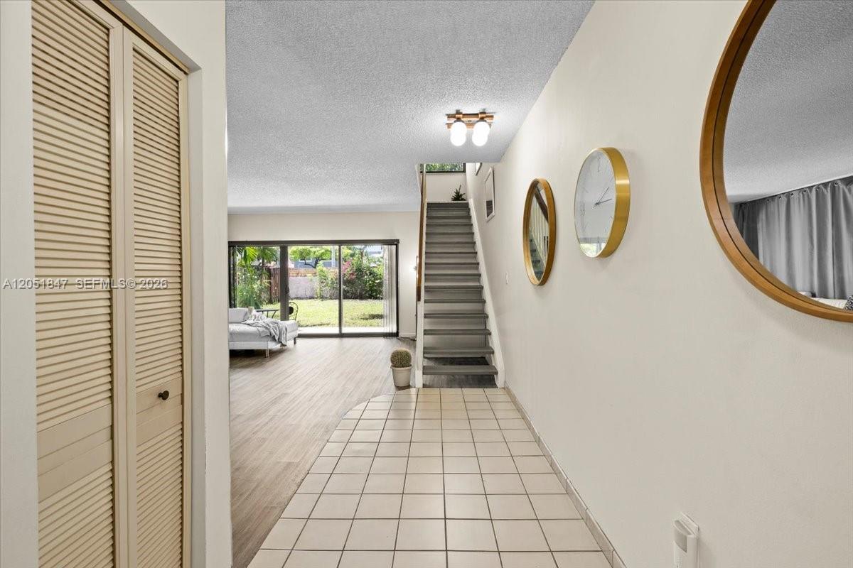 An entryway with tiled flooring leads to a living area with stairs and sliding doors — 19996 NE 5th Ct # 4C, Miami FL 33179, MIAMI, FL