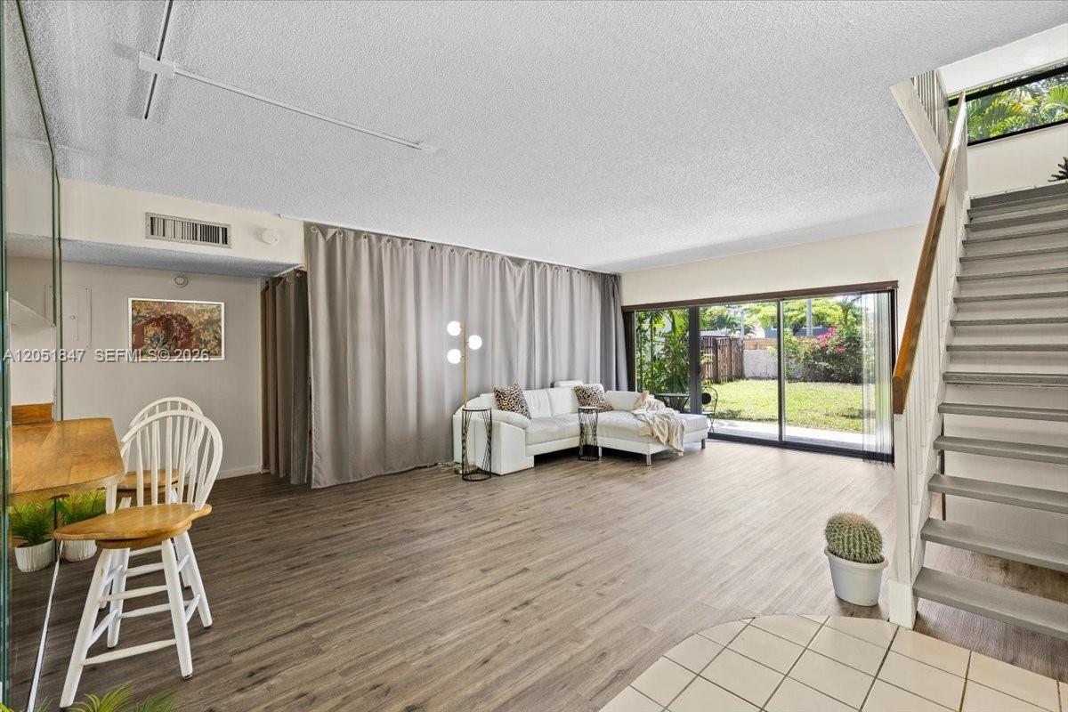 A living room features wood-look flooring, a white sectional sofa, and a staircase — 19996 NE 5th Ct # 4C, Miami FL 33179, MIAMI, FL
