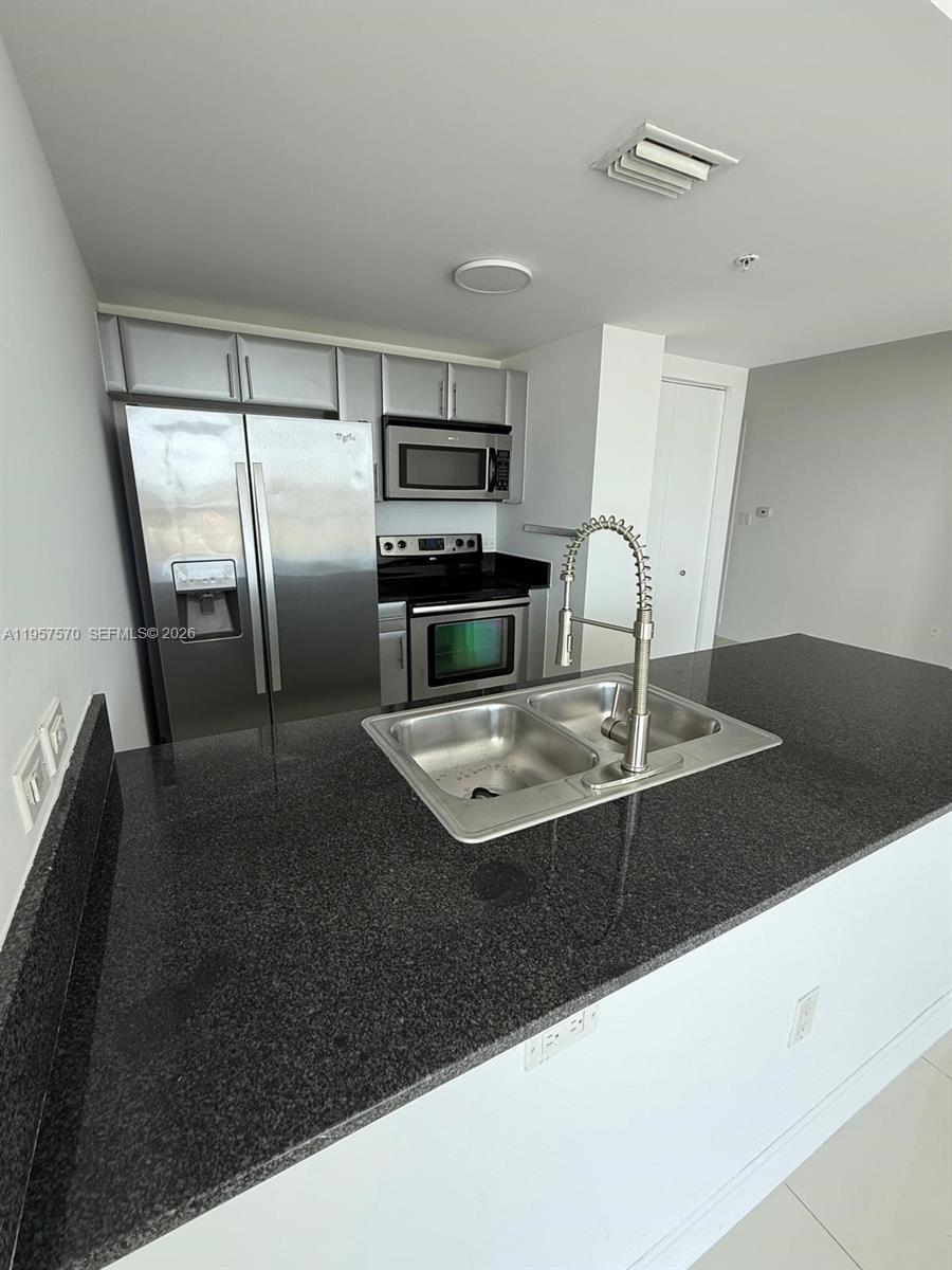 A kitchen features stainless steel appliances, dark granite countertops, and a double-basin sink — 1871 NW S River Dr # 1503, Miami FL 33125, MIAMI, FL