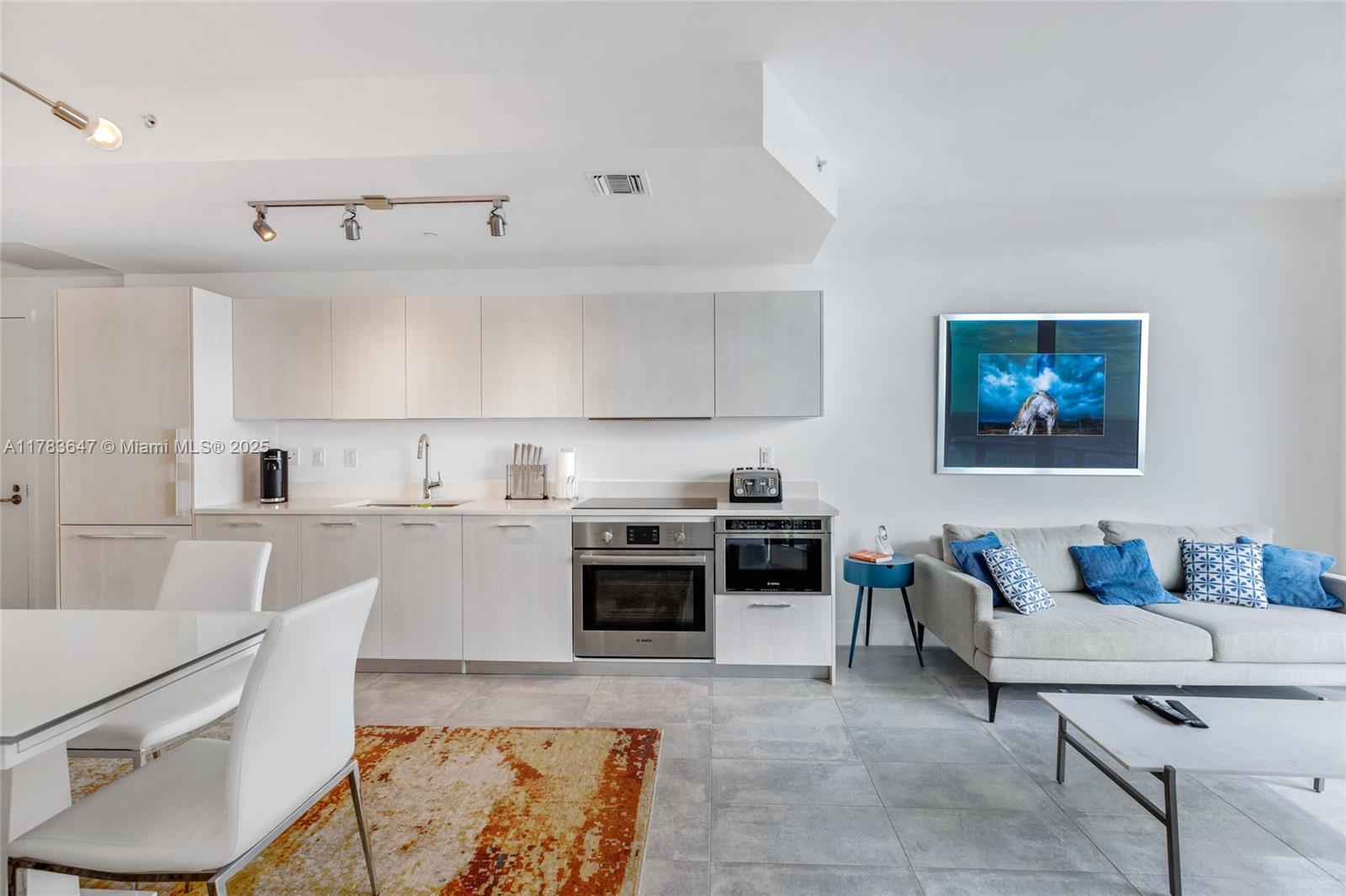 A modern open-concept kitchen and living area with light wood cabinetry and grey tile flooring — 501 NE 31 St # 3307, Miami FL 33137, MIAMI, FL