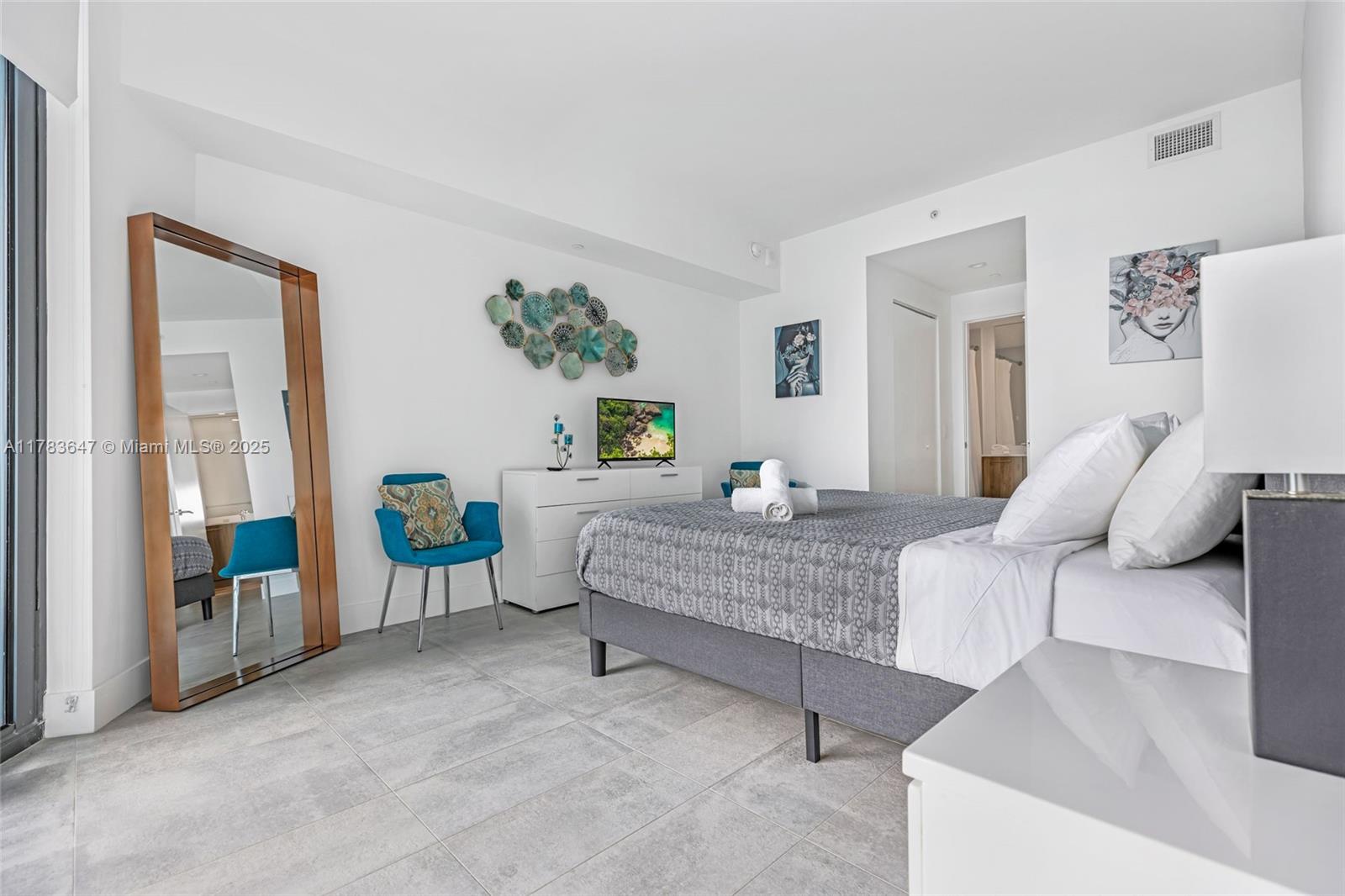 A bedroom features a bed, a dresser with a television, a floor mirror, and tile flooring — 501 NE 31 St # 3307, Miami FL 33137, MIAMI, FL