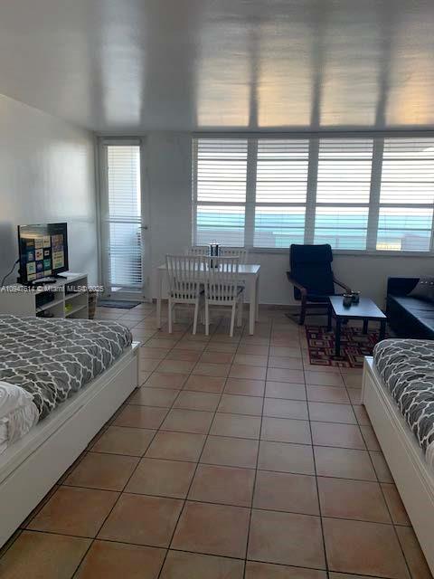 A bedroom with two beds, a dining set, and large windows overlooking the ocean — 100 Lincoln Rd # 1219, Miami Beach FL 33139, MIAMI BEACH, FL