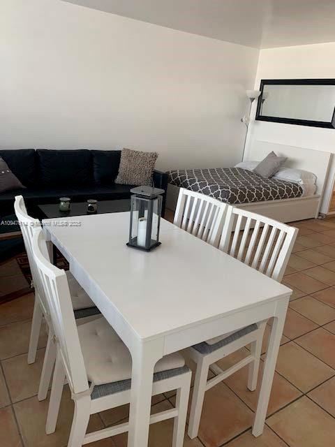 A white dining table with four chairs sits in a room with a sofa and bed — 100 Lincoln Rd # 1219, Miami Beach FL 33139, MIAMI BEACH, FL