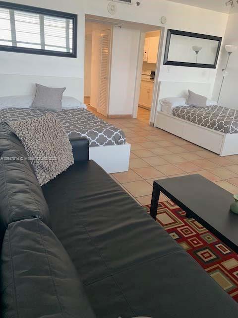 A room features a black sofa, two beds with patterned bedding, and a tiled floor — 100 Lincoln Rd # 1219, Miami Beach FL 33139, MIAMI BEACH, FL