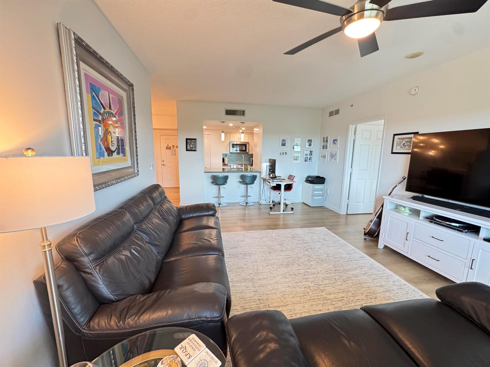 A living room with a dark leather sofa, a television, and an open kitchen area — 700 E Boynton Beach Boulevard # 608, Boynton Beach FL 33435, BOYNTON BEACH, FL
