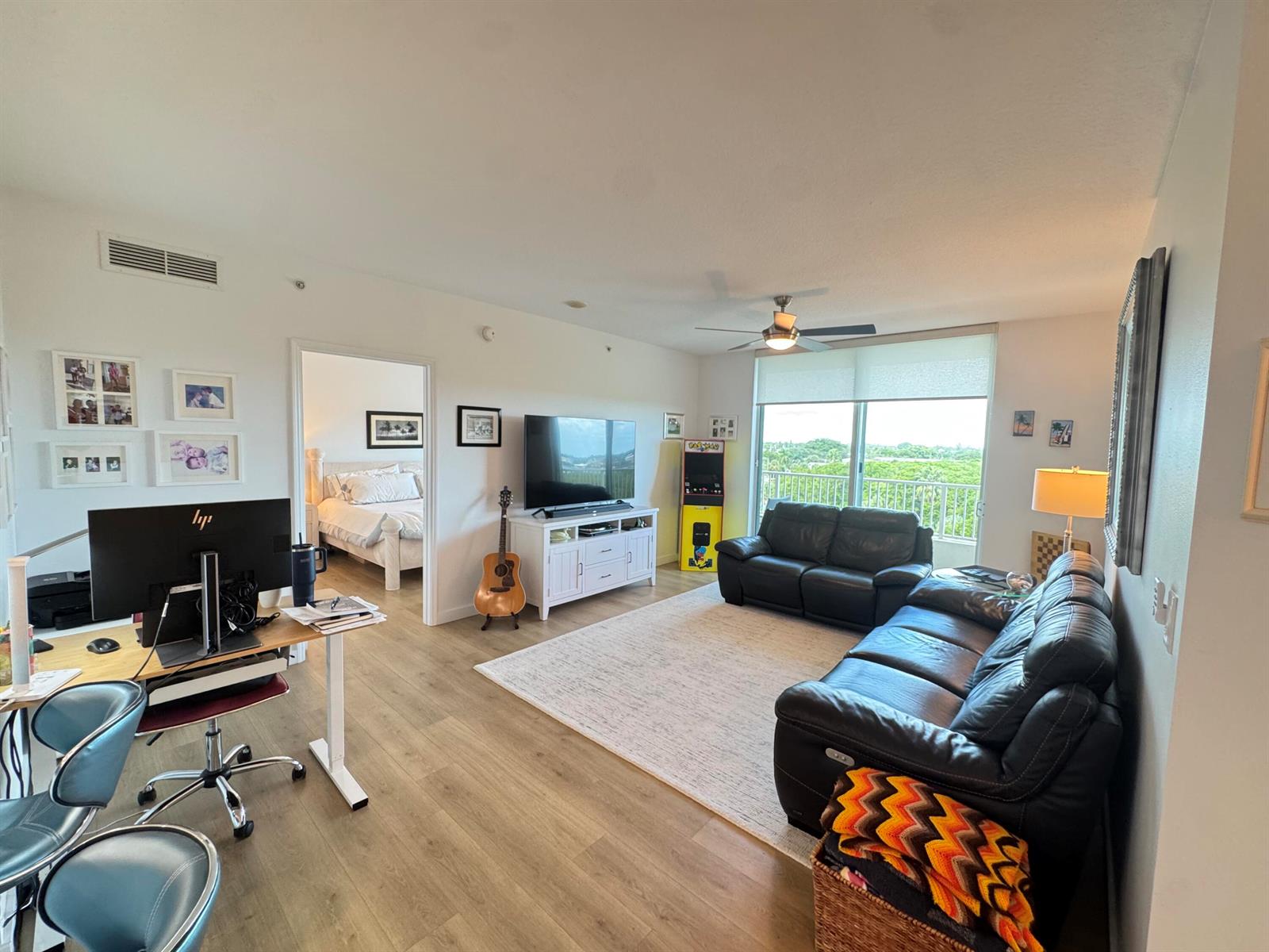 A living room with a desk, two black leather sofas, a television, and a balcony view — 700 E Boynton Beach Boulevard # 608, Boynton Beach FL 33435, BOYNTON BEACH, FL