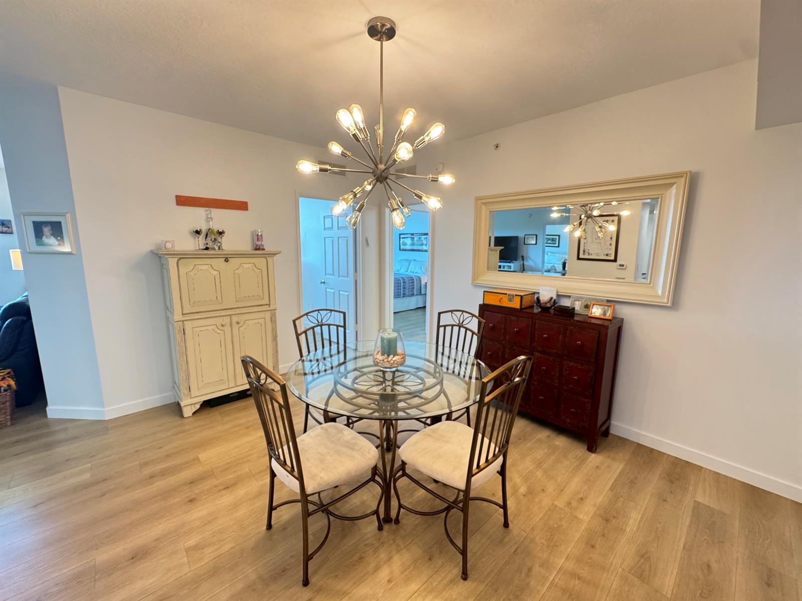A dining room features a glass-topped table, four chairs, a chandelier, and a large mirror — 700 E Boynton Beach Boulevard # 608, Boynton Beach FL 33435, BOYNTON BEACH, FL
