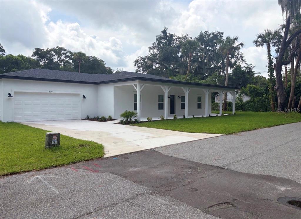 A white single-story house with a dark roof, a two-car garage, and a covered porch — 330 KIMBLE AVENUE, OVIEDO, FL