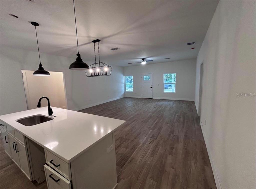 An open-concept kitchen with a white island and pendant lights overlooks a spacious living area — 330 KIMBLE AVENUE, OVIEDO, FL