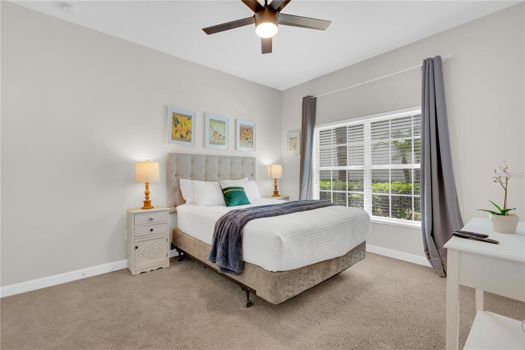 A bedroom features a queen bed, two nightstands with lamps, a window, and a ceiling fan — 4827 CLOCK TOWER DRIVE, KISSIMMEE, FL