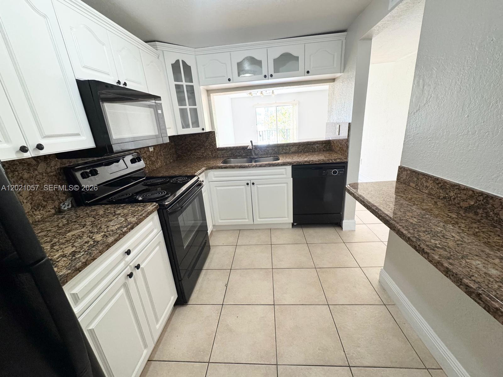 A kitchen features white cabinets, brown granite countertops, black appliances, and light tile flooring — 8600 SW 109th Ave # 202, Miami FL 33173, MIAMI, FL