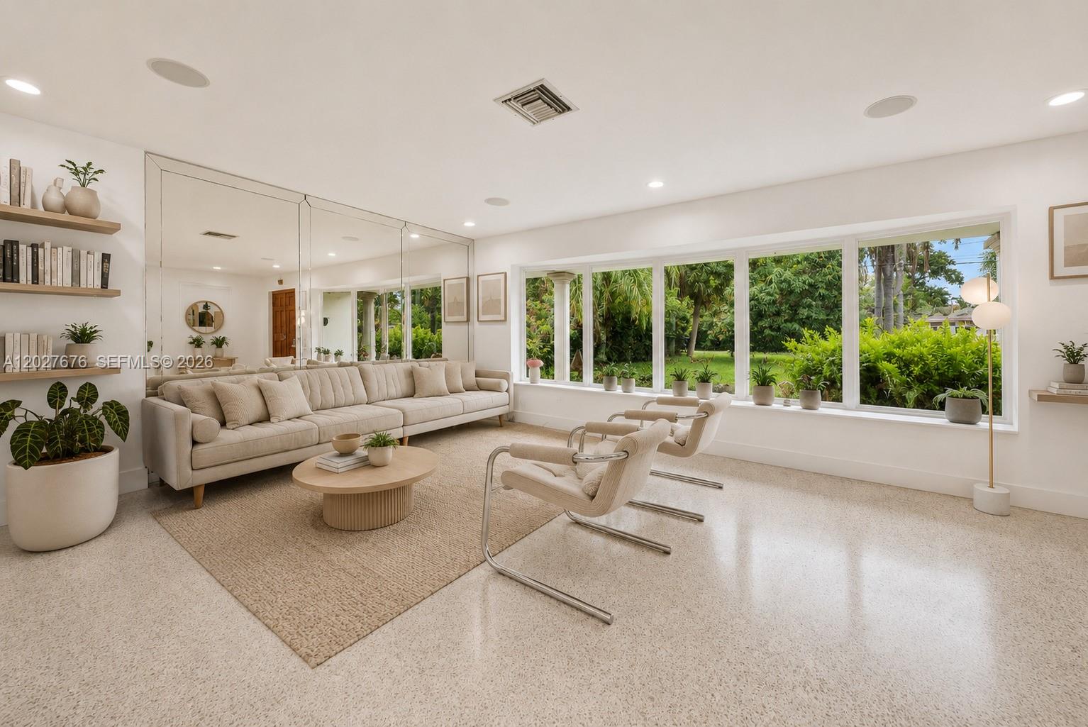 A bright living room features a large mirror, a beige sofa, and floor-to-ceiling windows — 14001 S Biscayne River Dr, Miami FL 33161, MIAMI, FL