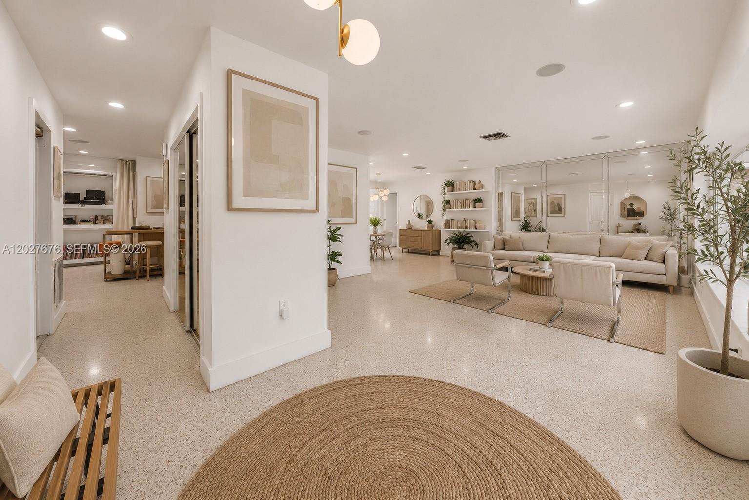 A bright, open-concept living area features terrazzo flooring, neutral furnishings, and a mirrored wall — 14001 S Biscayne River Dr, Miami FL 33161, MIAMI, FL